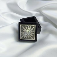 Small black trinket box with silver sun plaque on lid.