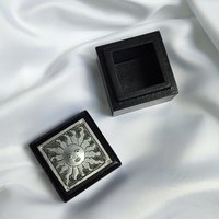 Small black trinket box with silver sun plaque on lid.
