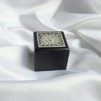 Small black trinket box with silver sun plaque on lid.