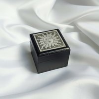 Small black trinket box with silver sun plaque on lid.
