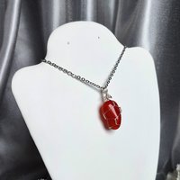 Carnelian pendant wrapped in silver plated wire with chain or cord.
