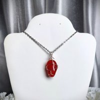 Carnelian pendant wrapped in silver plated wire with chain or cord.