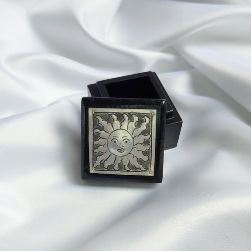 Small black trinket box with silver sun plaque on lid.
