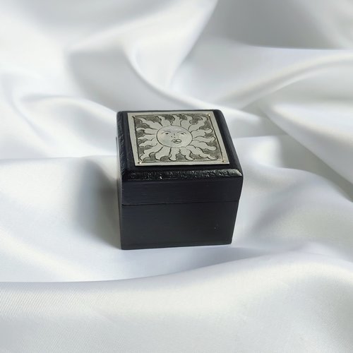 Small black trinket box with silver sun plaque on lid.