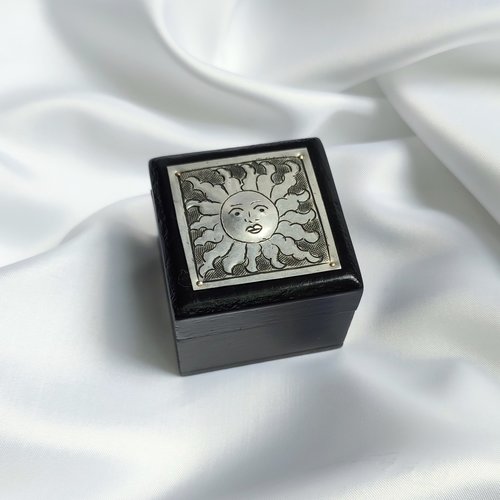 Small black trinket box with silver sun plaque on lid.
