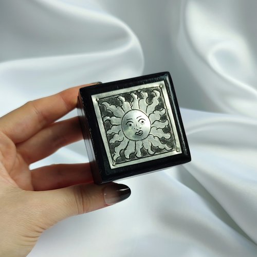 Small black trinket box with silver sun plaque on lid.