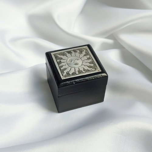Small black trinket box with silver sun plaque on lid.