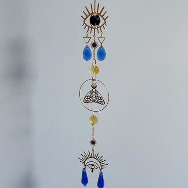 Egyptian Eye of Ra suncatcher with brass eyes, moth and yellow and blue glass crystals.